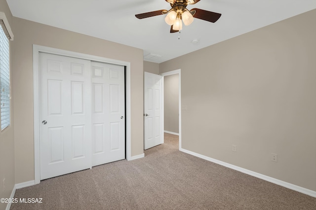 unfurnished bedroom featuring multiple windows, light colored carpet, a closet, and ceiling fan