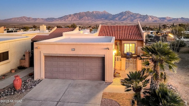 view of front facade with a tile roof, a mountain view, and stucco siding