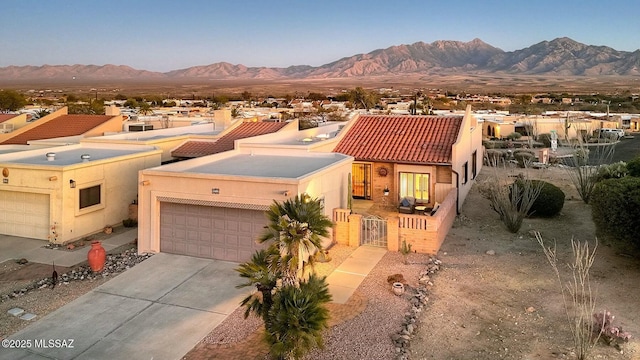 view of front of house with an attached garage, a mountain view, driveway, a gate, and stucco siding