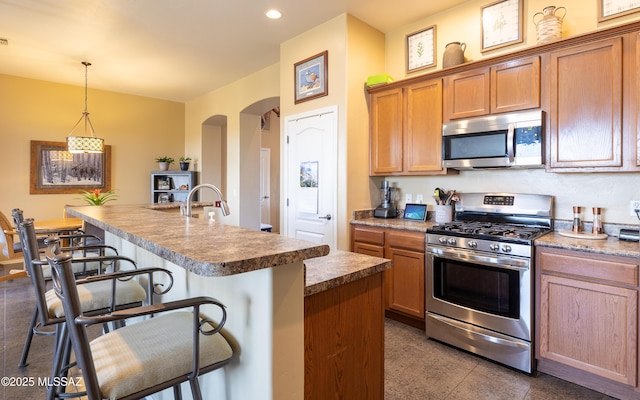 13289 E Wranglers Rest Dr, Vail, AZ 85641 - kitchen with appliances with stainless steel finishes, a breakfast bar area, arched walkways, an island with sink, and recessed lighting