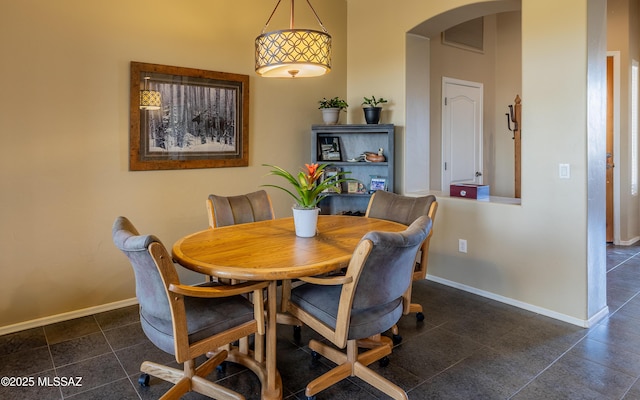 13289 E Wranglers Rest Dr, Vail, AZ 85641 - dining area featuring arched walkways, baseboards, dark tile patterned flooring, and a towering ceiling