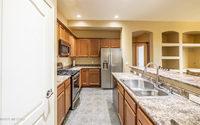 13289 E Wranglers Rest Dr, Vail, AZ 85641 - kitchen featuring stainless steel appliances, a sink, brown cabinetry, arched walkways, and recessed lighting
