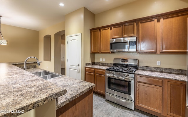 13289 E Wranglers Rest Dr, Vail, AZ 85641 - kitchen with stainless steel appliances, a sink, arched walkways, brown cabinets, and recessed lighting