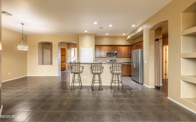 13289 E Wranglers Rest Dr, Vail, AZ 85641 - kitchen with stainless steel appliances, recessed lighting, brown cabinets, a breakfast bar, and baseboards