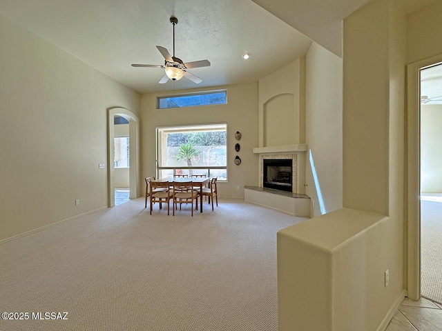 unfurnished dining area with ceiling fan, light colored carpet, and a fireplace