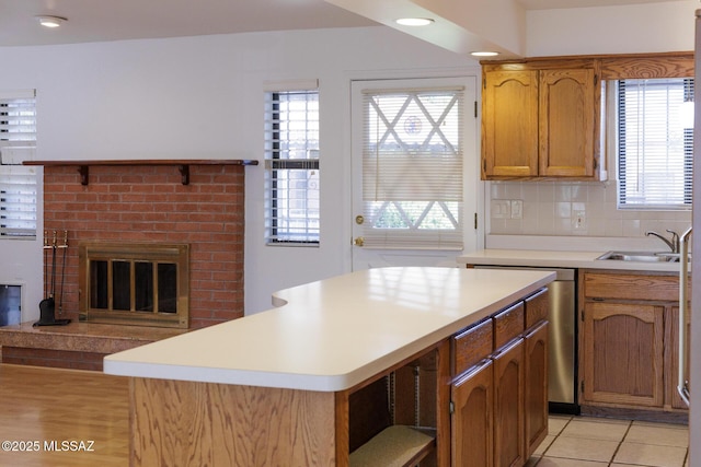 kitchen with light countertops, a sink, a fireplace, light tile patterned floors, and decorative backsplash