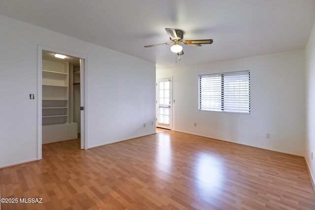 empty room with a ceiling fan, baseboards, and light wood-style floors