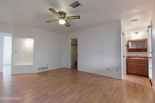 spare room with a sink, ceiling fan, visible vents, and light wood-type flooring