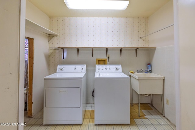 laundry room featuring laundry area, a sink, separate washer and dryer, and wallpapered walls