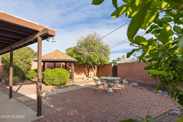 view of patio with outdoor dining space, fence, and a gazebo