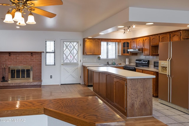 kitchen featuring light countertops, under cabinet range hood, black range with electric cooktop, white fridge with ice dispenser, and brown cabinets