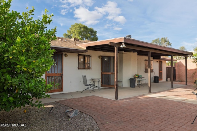 rear view of house featuring stucco siding and a patio area