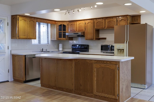 kitchen featuring a sink, stainless steel appliances, brown cabinetry, and under cabinet range hood