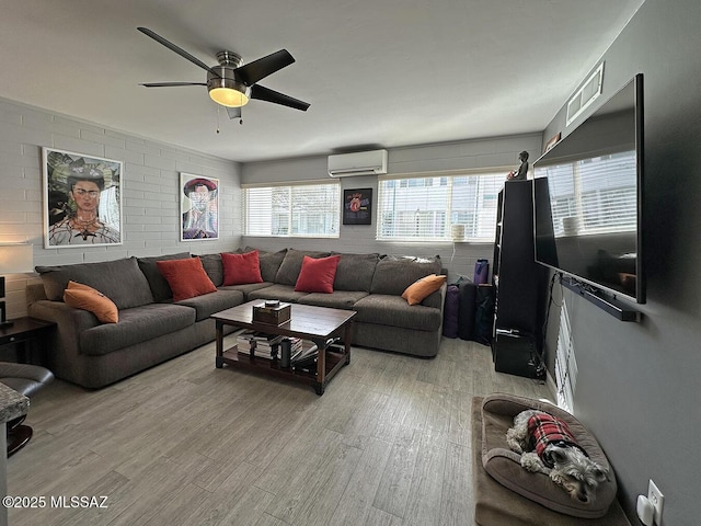 living room with ceiling fan, an AC wall unit, and light wood-type flooring