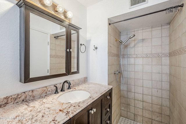 bathroom featuring a tile shower and vanity