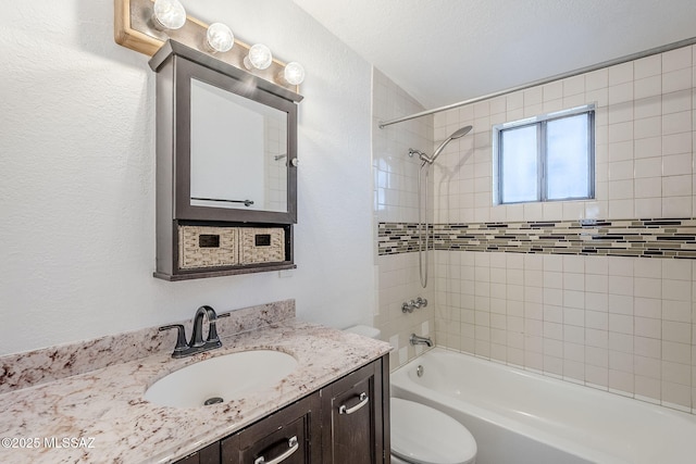 full bathroom featuring vanity, tiled shower / bath combo, and toilet