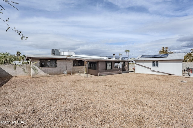 rear view of house with a sunroom and solar panels