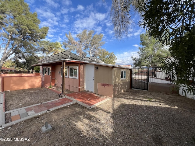 rear view of house featuring fence and a gate