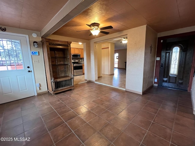 entryway with ceiling fan, dark tile patterned floors, and baseboards