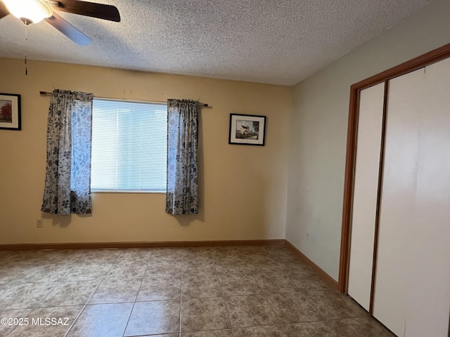 unfurnished room with ceiling fan, a textured ceiling, tile patterned floors, and baseboards