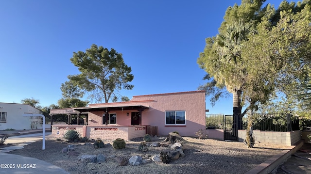 view of front of property with a gate, fence, and stucco siding