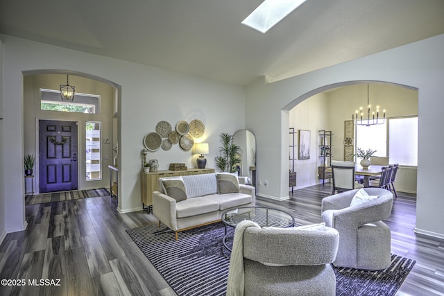 living area featuring an inviting chandelier, a wealth of natural light, wood finished floors, and arched walkways