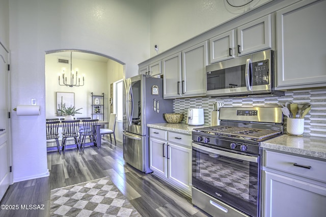 kitchen featuring dark wood-style floors, visible vents, backsplash, arched walkways, and appliances with stainless steel finishes