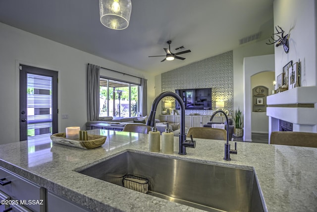kitchen featuring a sink, visible vents, open floor plan, vaulted ceiling, and a ceiling fan