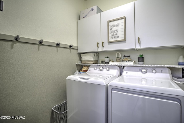 laundry room featuring independent washer and dryer, a textured wall, and cabinet space