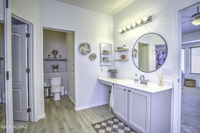 full bathroom with baseboards, wood finished floors, toilet, and vanity