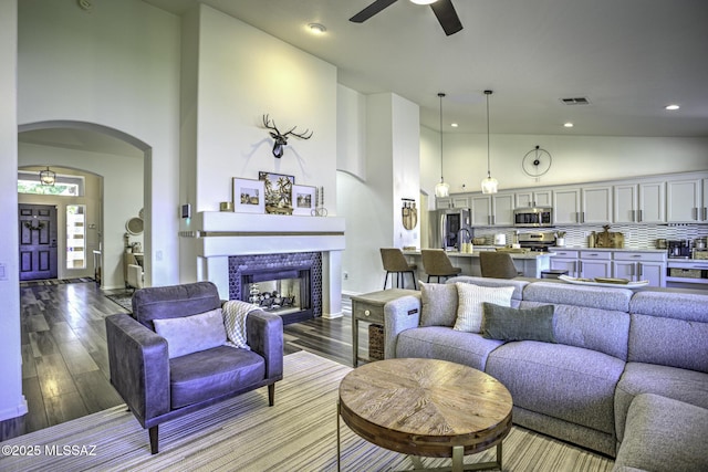 living room with wood finished floors, ceiling fan, high vaulted ceiling, and arched walkways