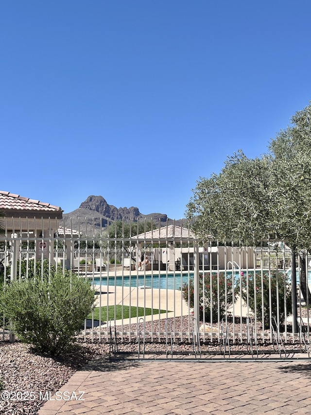 community pool with a mountain view, fence, and a pergola