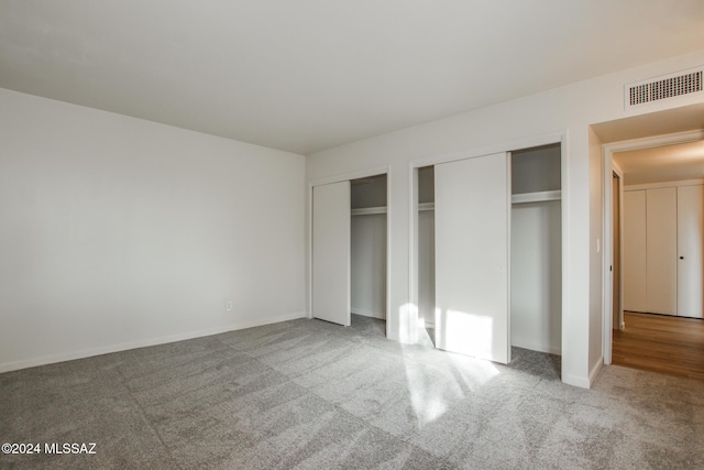 unfurnished bedroom featuring carpet floors and two closets