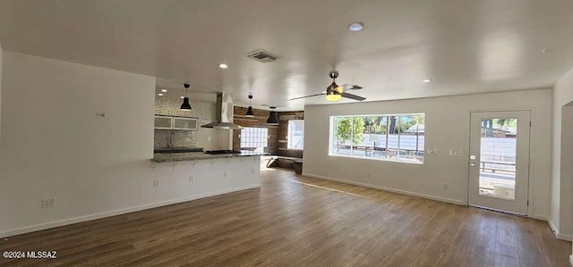 unfurnished living room featuring sink, hardwood / wood-style flooring, and ceiling fan