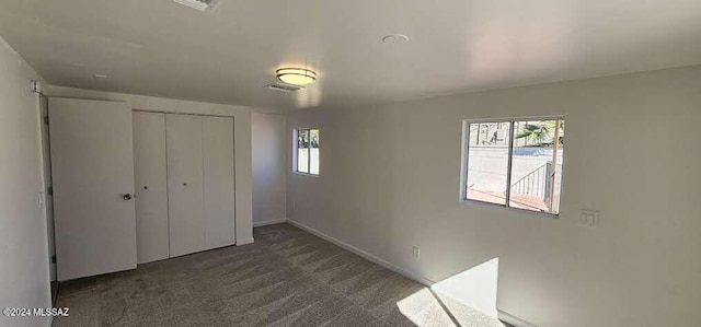 unfurnished bedroom with dark carpet and a closet