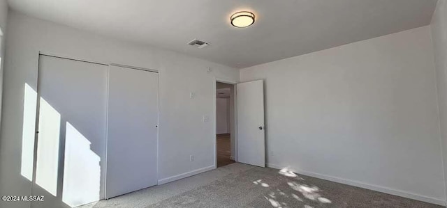 unfurnished bedroom featuring light carpet and a closet