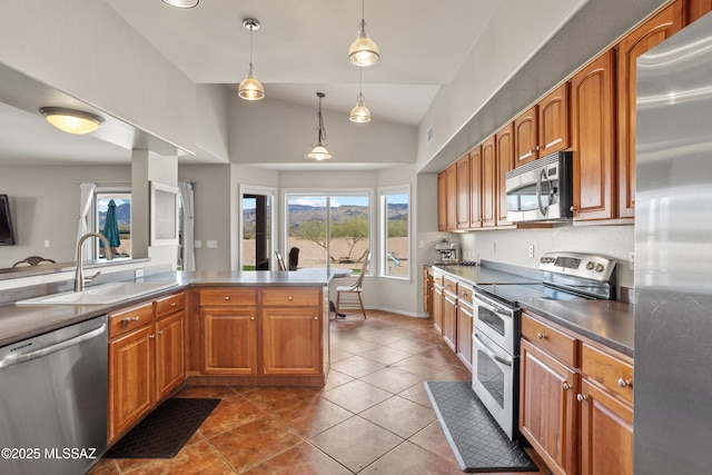 kitchen featuring appliances with stainless steel finishes, pendant lighting, lofted ceiling, sink, and tile patterned floors