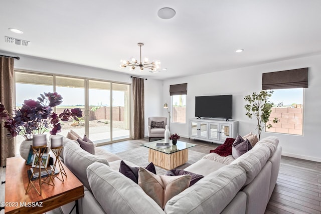 living area with baseboards, wood finished floors, visible vents, and a notable chandelier