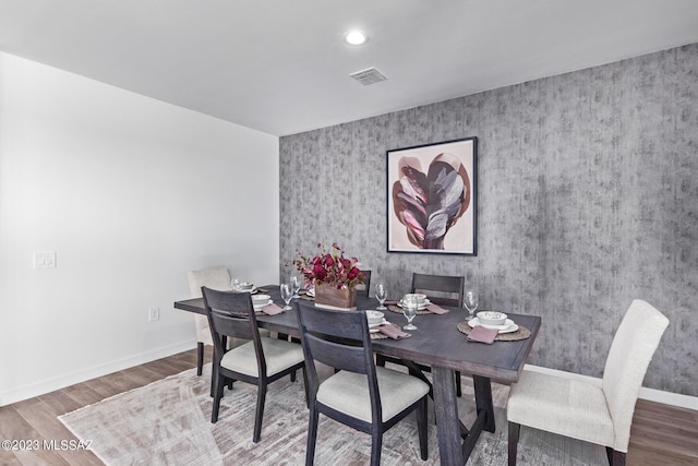dining room with visible vents, wood finished floors, baseboards, an accent wall, and recessed lighting