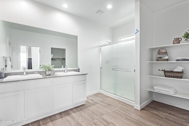 full bath with double vanity, a sink, wood finished floors, and a shower stall