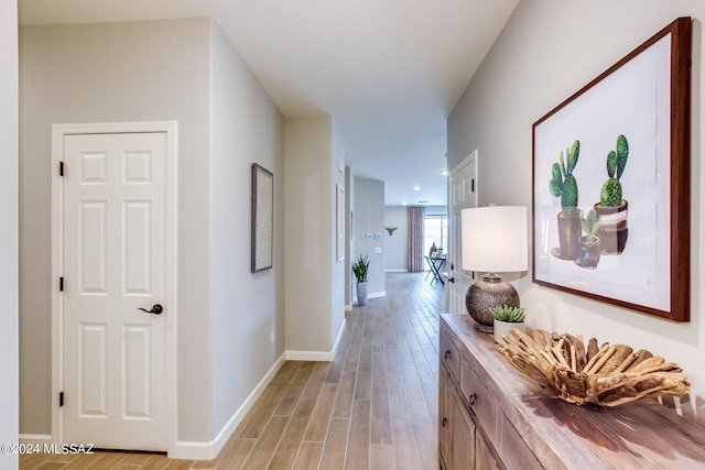 corridor with baseboards and light wood-style flooring