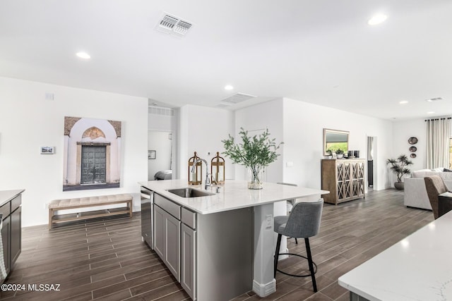 kitchen with sink, gray cabinets, a breakfast bar, a kitchen island with sink, and stainless steel dishwasher