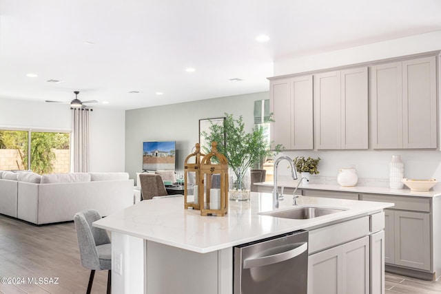 kitchen with sink, light hardwood / wood-style flooring, gray cabinets, dishwasher, and a center island with sink