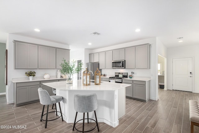 kitchen featuring stainless steel appliances, a breakfast bar, and gray cabinetry