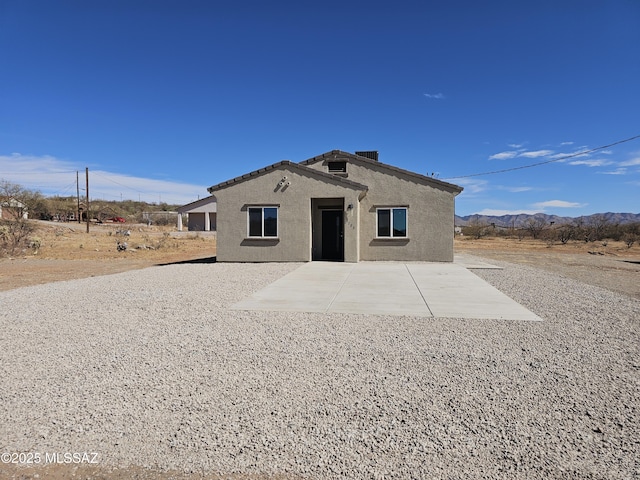 exterior space with a patio area, a mountain view, and stucco siding