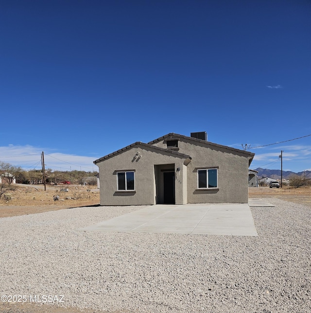 view of front of property featuring a patio area, cooling unit, and stucco siding