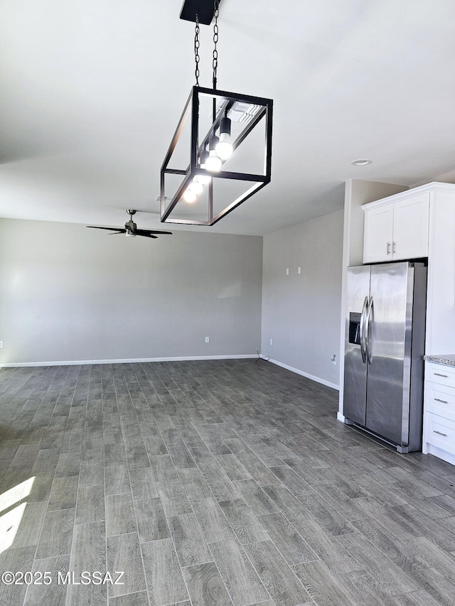 interior space featuring ceiling fan, stainless steel refrigerator with ice dispenser, and baseboards