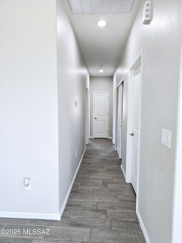 hallway featuring visible vents, baseboards, and wood finished floors