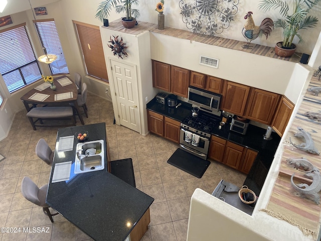 kitchen with stainless steel appliances, a towering ceiling, and light tile patterned floors