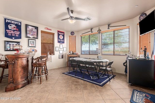 tiled dining space featuring bar and ceiling fan